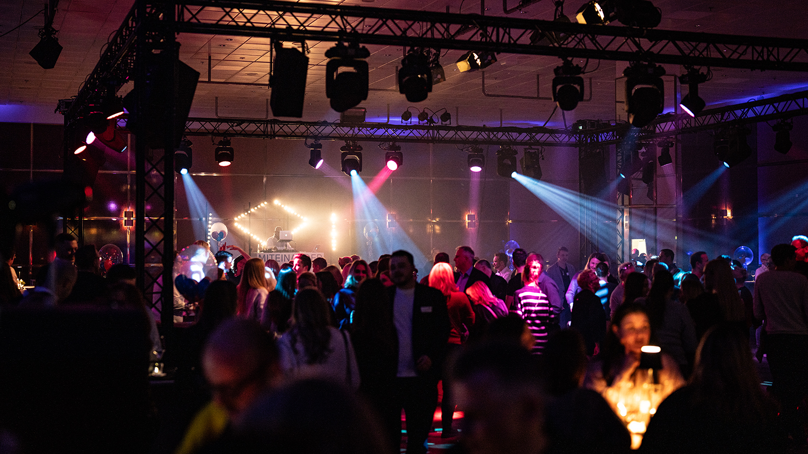 Gäste tanzen auf der Zukunftstag-Party, im Hintergrund ein DJ-Pult mit Lichtshow